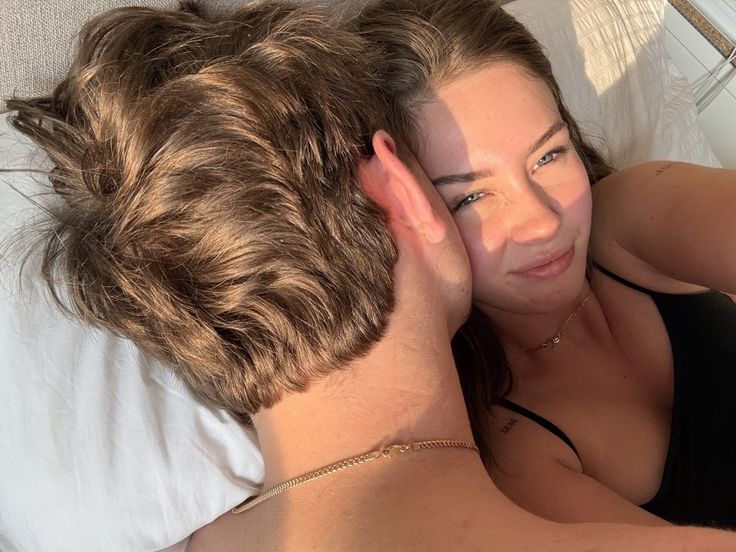 A couple embraces in bed in warm morning light.